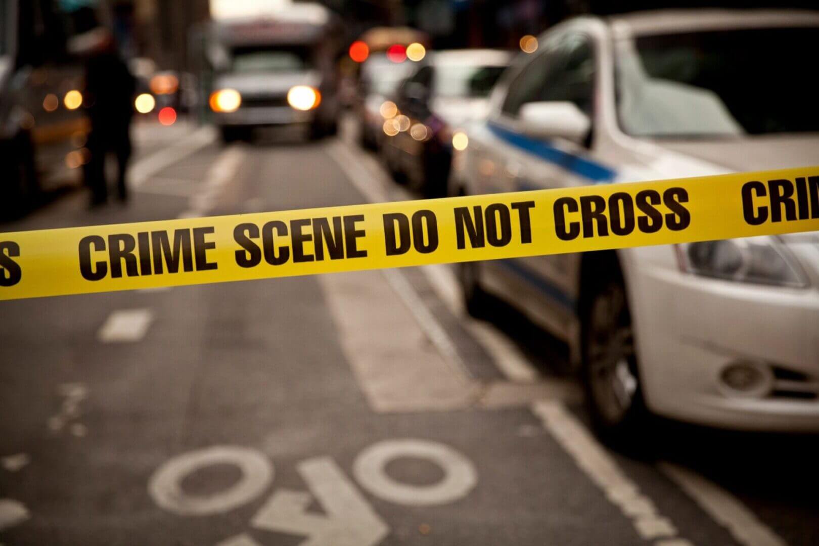 A police tape is shown on the side of a road.
